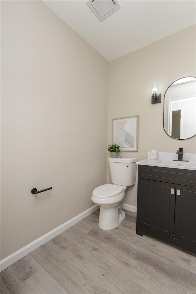 bathroom with toilet, hardwood / wood-style floors, and vanity