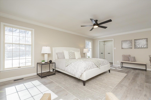 bedroom featuring ceiling fan, multiple windows, and light hardwood / wood-style flooring