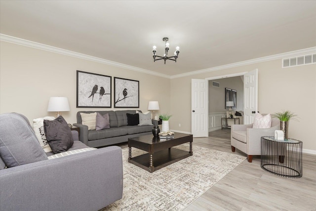 living room with light wood-type flooring, crown molding, and a chandelier