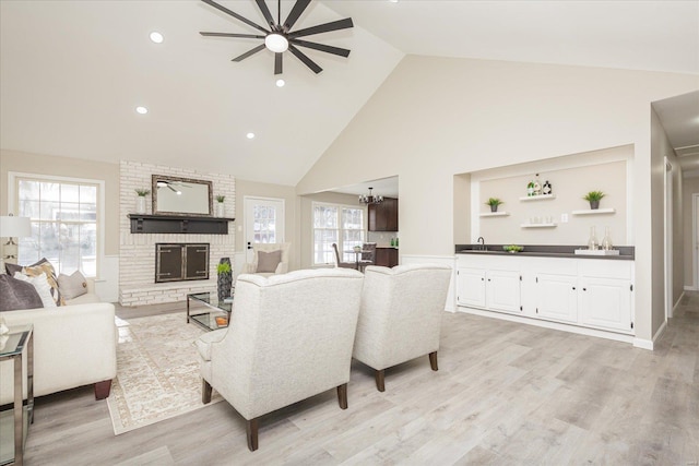 living room featuring light wood-type flooring, a healthy amount of sunlight, a fireplace, and high vaulted ceiling