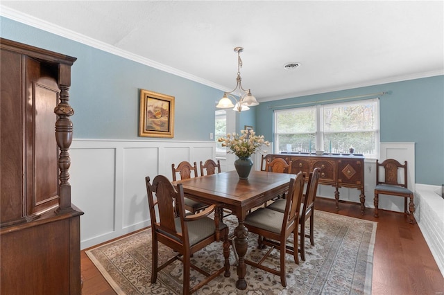 dining room with dark hardwood / wood-style flooring, ornamental molding, and a notable chandelier