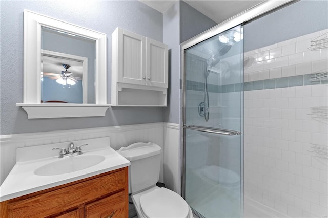 bathroom featuring vanity, toilet, an enclosed shower, and ceiling fan