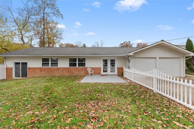 back of property with french doors, a patio, a garage, and a lawn