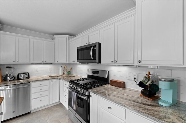 kitchen featuring appliances with stainless steel finishes, backsplash, light stone counters, ornamental molding, and white cabinets