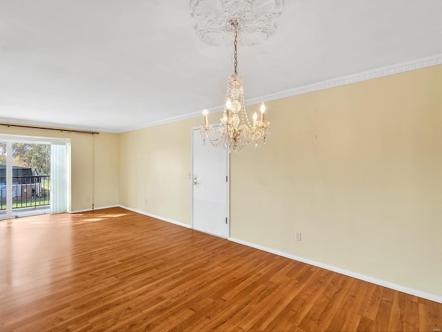 spare room featuring a chandelier, hardwood / wood-style floors, and ornamental molding