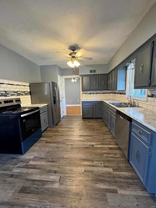 kitchen with stainless steel appliances, backsplash, sink, dark wood-type flooring, and ceiling fan