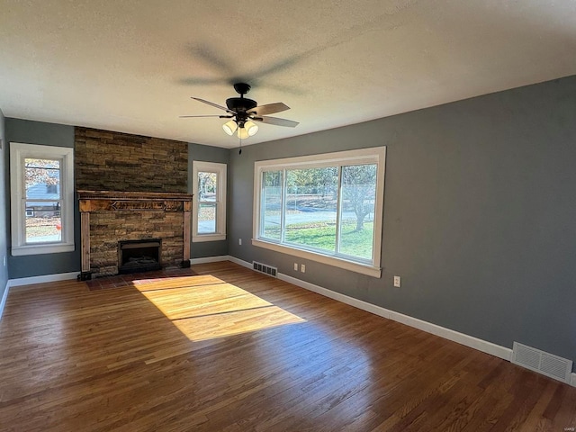 unfurnished living room with ceiling fan, hardwood / wood-style flooring, a healthy amount of sunlight, and a fireplace