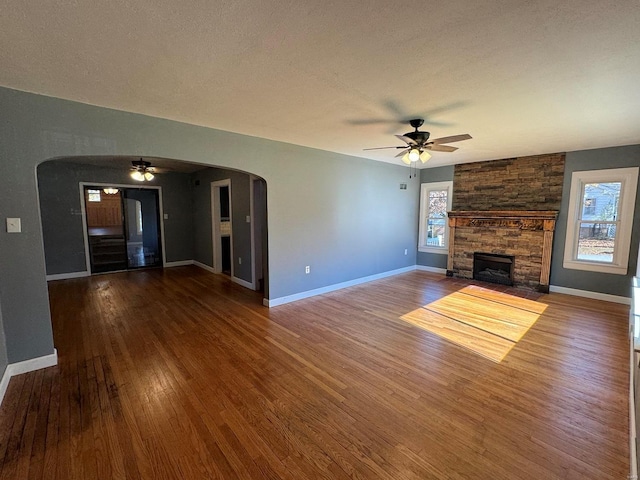 unfurnished living room featuring a fireplace, hardwood / wood-style flooring, ceiling fan, and a textured ceiling