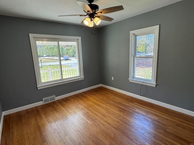 spare room with ceiling fan, wood-type flooring, and a healthy amount of sunlight