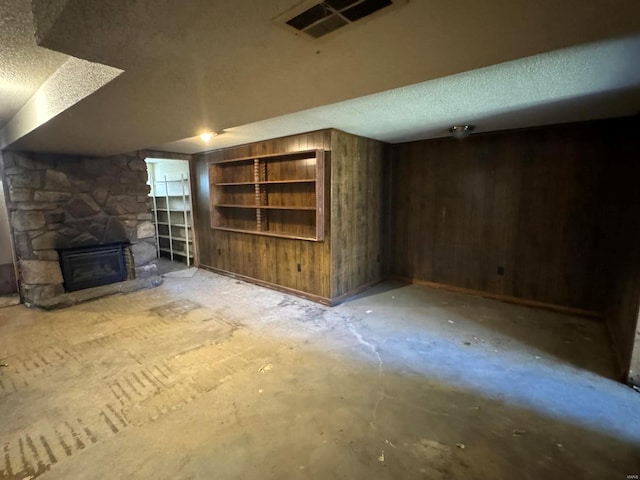 unfurnished living room with wood walls, a fireplace, and a textured ceiling