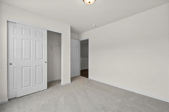 unfurnished bedroom with light colored carpet and a closet