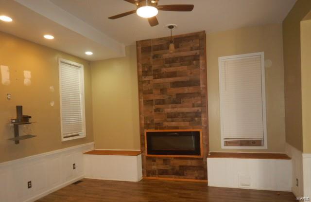 unfurnished living room with a fireplace, dark hardwood / wood-style flooring, and ceiling fan