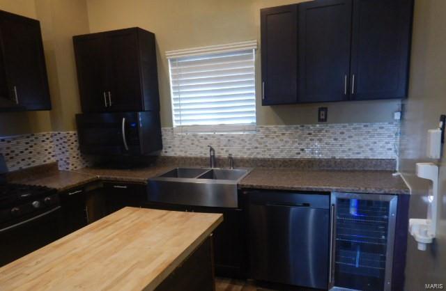 kitchen with backsplash, beverage cooler, sink, and black appliances