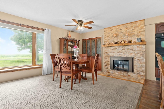 dining room featuring hardwood / wood-style floors, ceiling fan, and a fireplace