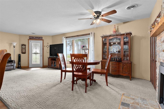 dining area with ceiling fan, a textured ceiling, and light carpet