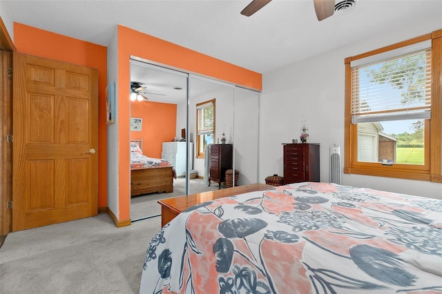 bedroom featuring light carpet, ceiling fan, multiple windows, and a closet