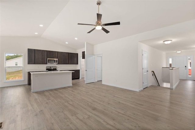 kitchen featuring appliances with stainless steel finishes, a center island with sink, vaulted ceiling, and light hardwood / wood-style flooring