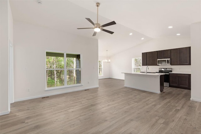 unfurnished living room with light hardwood / wood-style floors, ceiling fan with notable chandelier, sink, and lofted ceiling