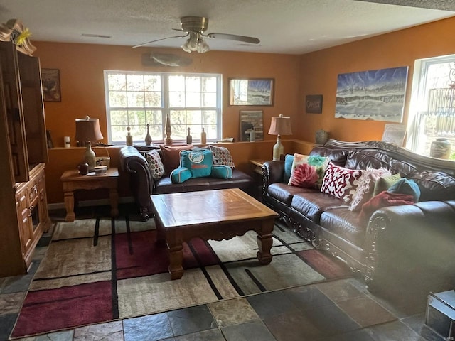 living room with a textured ceiling and ceiling fan