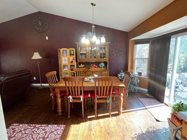 dining area with dark hardwood / wood-style flooring, lofted ceiling, and a notable chandelier