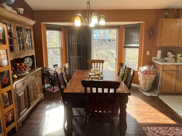 dining space with dark hardwood / wood-style flooring and an inviting chandelier