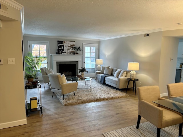 living room featuring hardwood / wood-style flooring, ornamental molding, a fireplace, and a textured ceiling