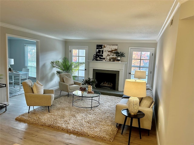 living room with a fireplace, wood-type flooring, ornamental molding, and a wealth of natural light