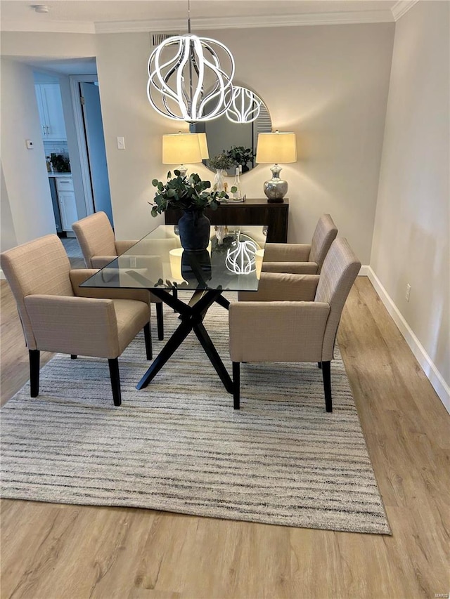 dining room with light hardwood / wood-style floors, ornamental molding, and a chandelier