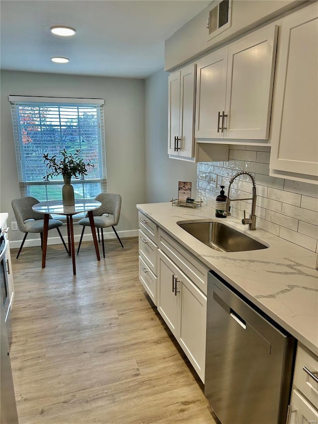 kitchen with white cabinets, light stone counters, sink, light hardwood / wood-style flooring, and dishwasher