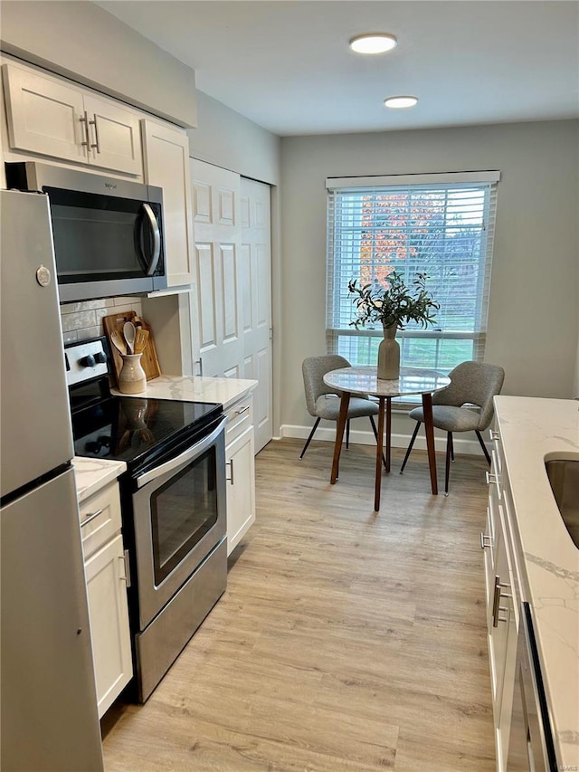 kitchen with light stone counters, white cabinetry, and stainless steel appliances