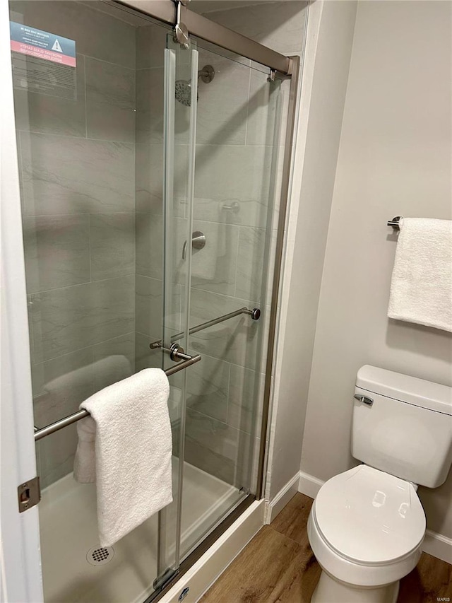 bathroom with walk in shower, toilet, and hardwood / wood-style flooring