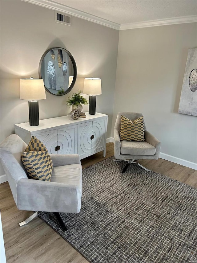 sitting room with crown molding and hardwood / wood-style flooring