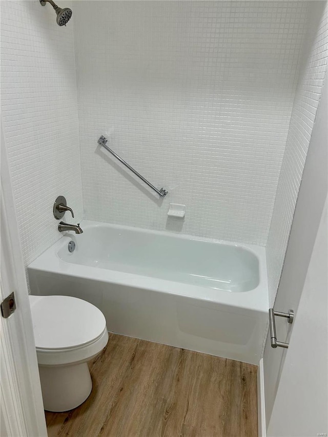 bathroom with tiled shower / bath combo, hardwood / wood-style flooring, and toilet