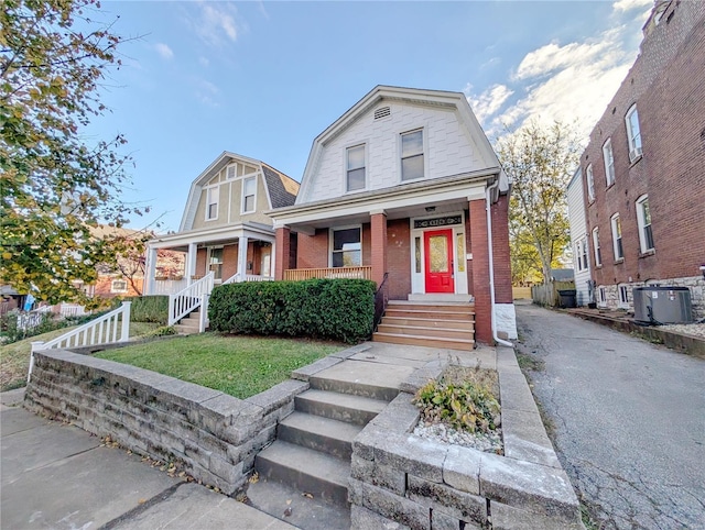 view of front of home with central AC, covered porch, and a front lawn