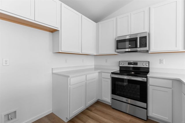 kitchen featuring lofted ceiling, white cabinetry, light wood-type flooring, and appliances with stainless steel finishes