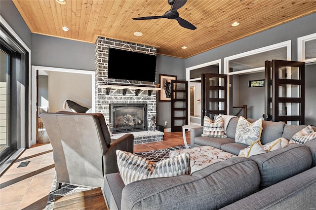 tiled living room with a stone fireplace, wood ceiling, and ceiling fan