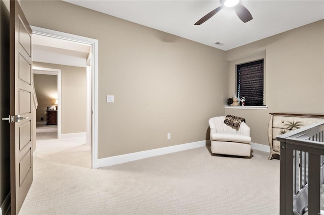 bedroom with a crib, light colored carpet, and ceiling fan