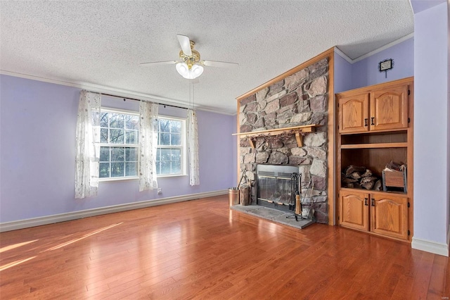 unfurnished living room with a fireplace, hardwood / wood-style floors, a textured ceiling, and ornamental molding