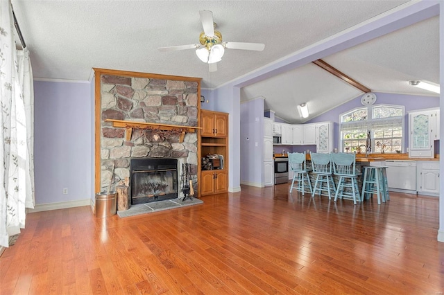 unfurnished living room featuring ceiling fan, light hardwood / wood-style flooring, lofted ceiling with beams, a textured ceiling, and a fireplace