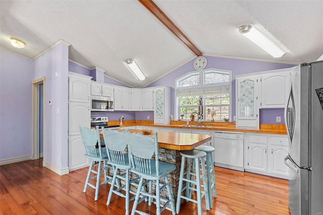 kitchen with white cabinets, appliances with stainless steel finishes, a center island, and light hardwood / wood-style floors