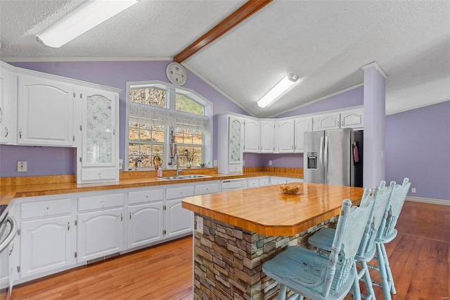 kitchen featuring sink, stainless steel refrigerator with ice dispenser, light hardwood / wood-style flooring, a textured ceiling, and white cabinetry