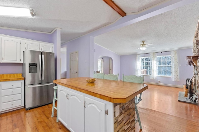 kitchen featuring a kitchen bar, stainless steel fridge, white cabinets, and light hardwood / wood-style floors