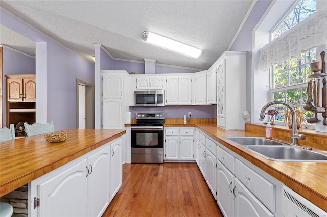 kitchen with a textured ceiling, appliances with stainless steel finishes, and vaulted ceiling