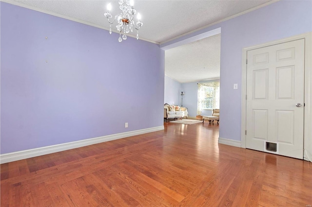 unfurnished dining area featuring hardwood / wood-style floors, a textured ceiling, an inviting chandelier, and ornamental molding