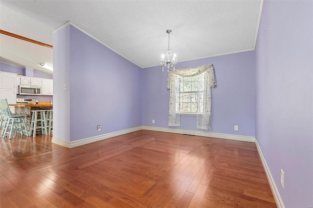 empty room featuring hardwood / wood-style floors, a textured ceiling, and ornamental molding