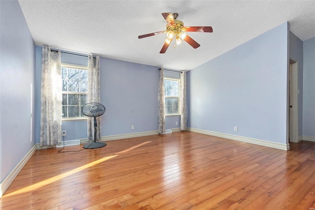 empty room with a textured ceiling, light hardwood / wood-style flooring, and a healthy amount of sunlight