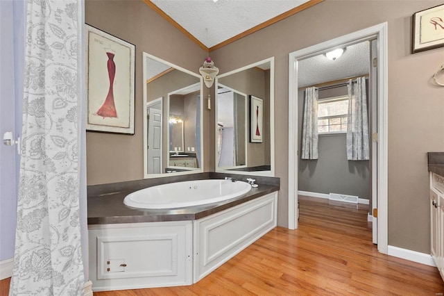 bathroom with hardwood / wood-style floors, ornamental molding, and a textured ceiling