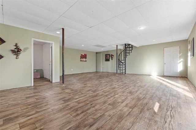 unfurnished living room with a paneled ceiling and wood-type flooring