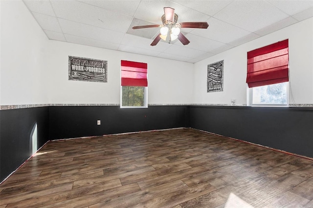 empty room with a paneled ceiling, ceiling fan, and hardwood / wood-style floors