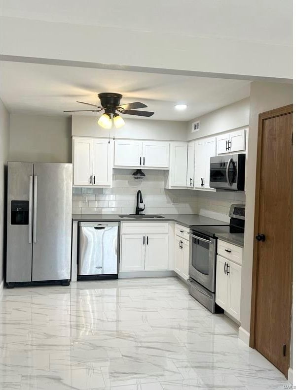 kitchen with decorative backsplash, stainless steel appliances, white cabinets, and sink